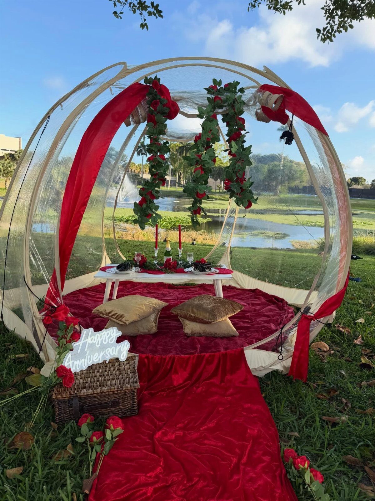 Clear bubble tent with red carpet, pillows, and snacks by a scenic lake