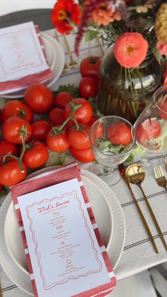 Themed dinner table setting with red tomatoes, floral centerpiece, and printed menus.