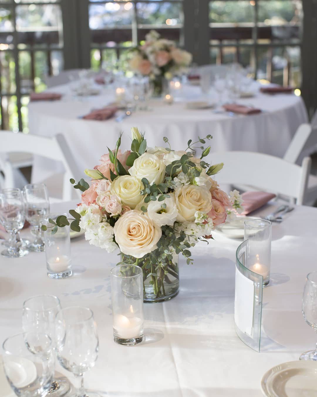 White and pink rose centerpiece with floating candles on a white wedding table.
