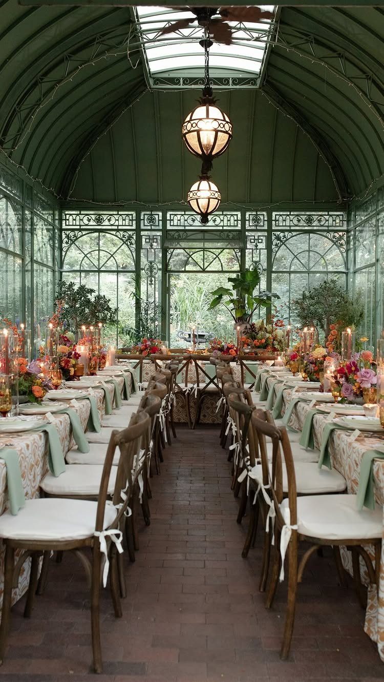 Long wedding dining table with autumn florals inside a glass conservatory greenhouse
