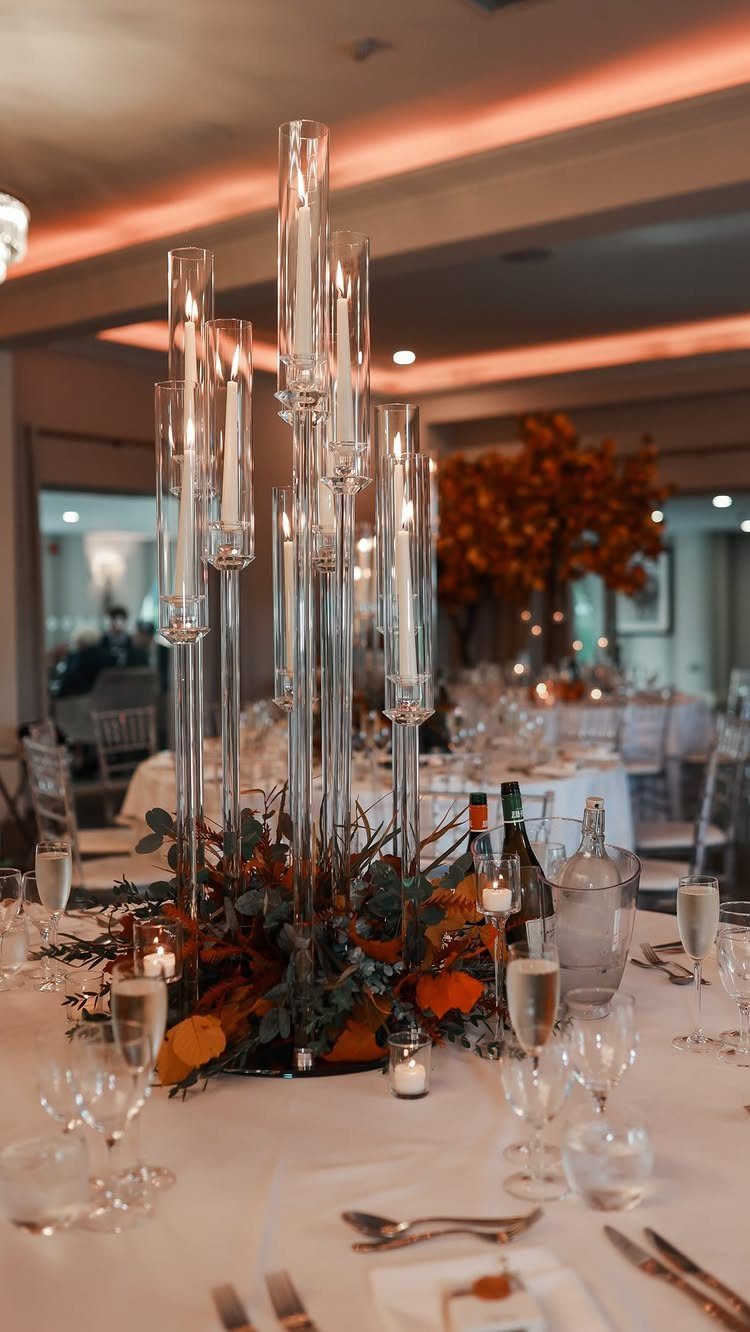 Tall glass cylinder taper candles with autumn foliage as a wedding table centerpiece.