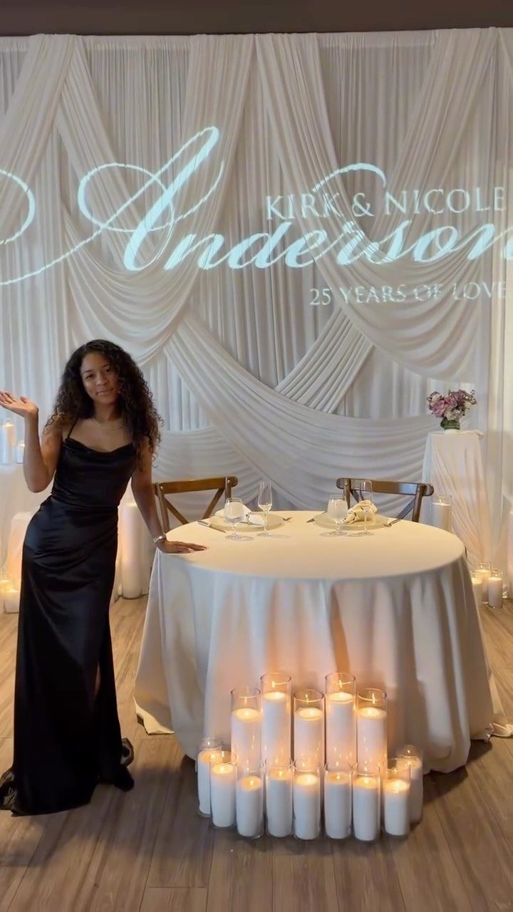 Woman in black dress standing by a decorated table with anniversary projection backdrop