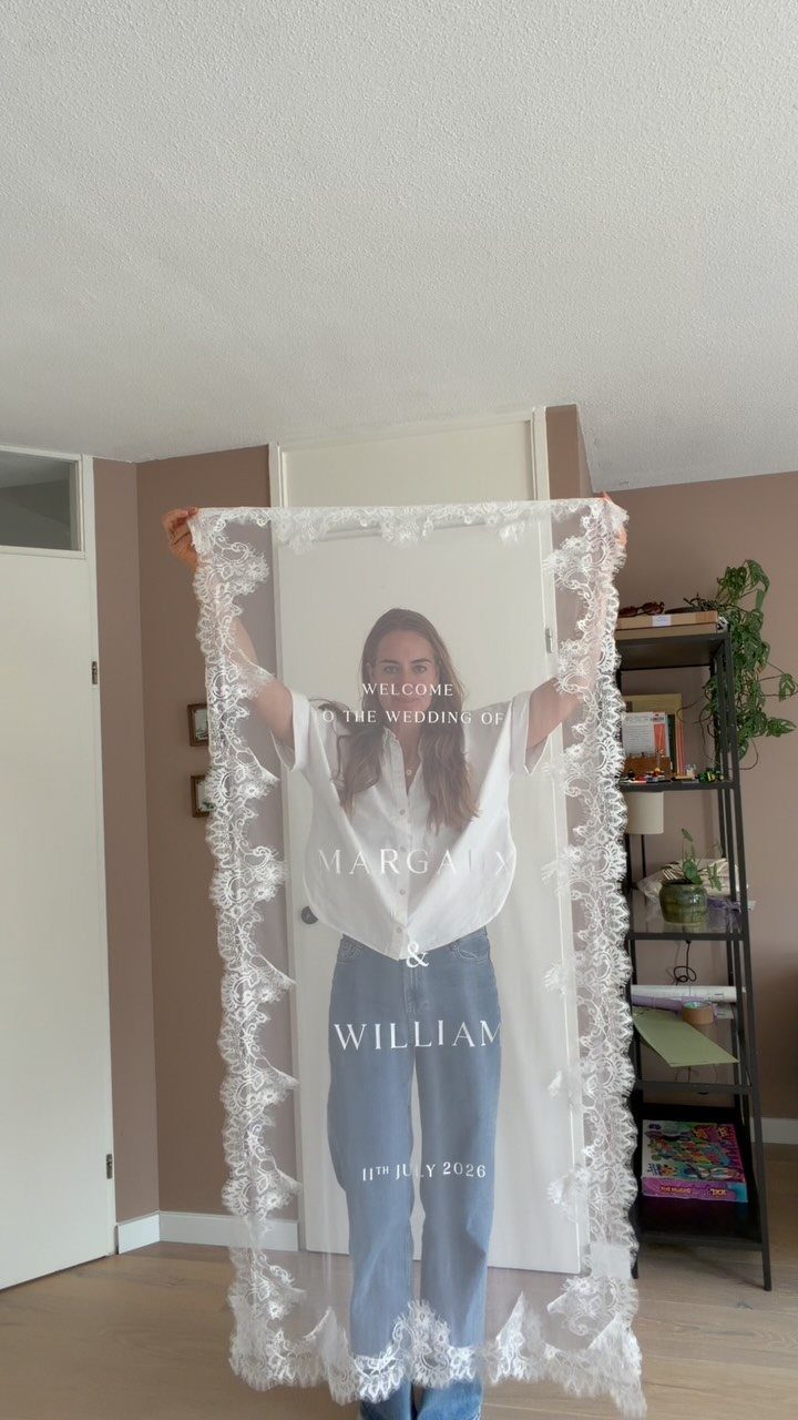 Transparent acrylic wedding welcome sign with white lace borders held by a woman.