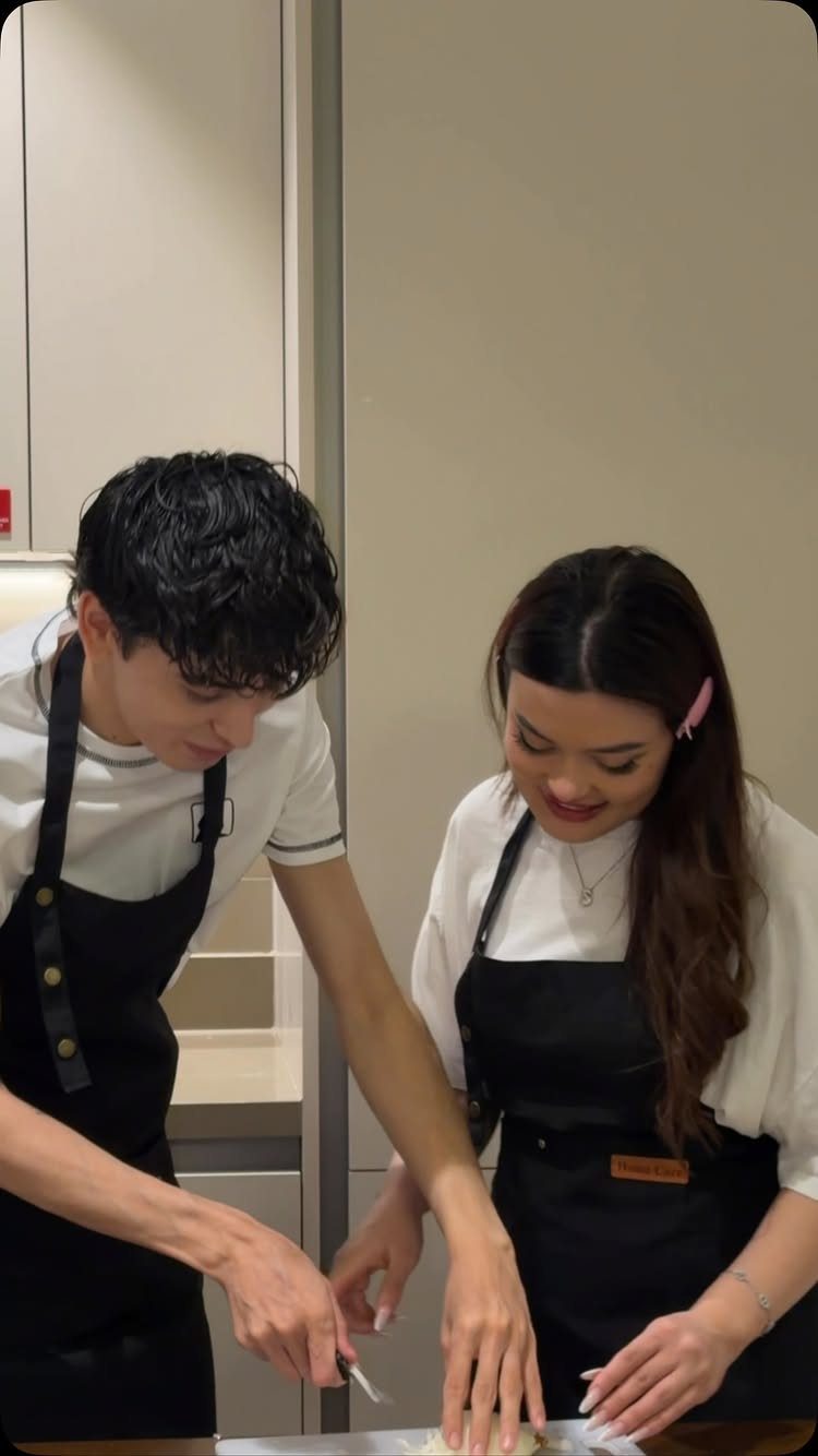Young couple in black aprons preparing food together in a modern kitchen.