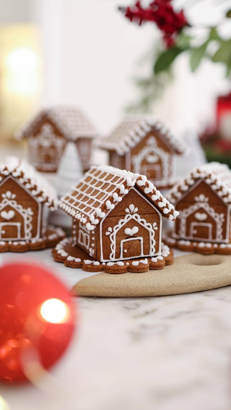 Small gingerbread houses with white icing decorations on a white marble surface.