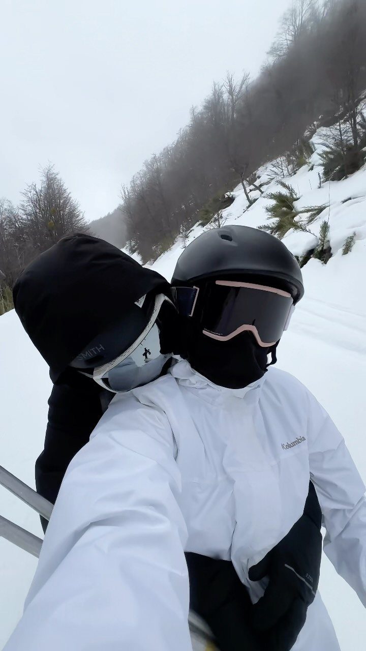 Two people in ski gear posing together on a snowy mountain slope.