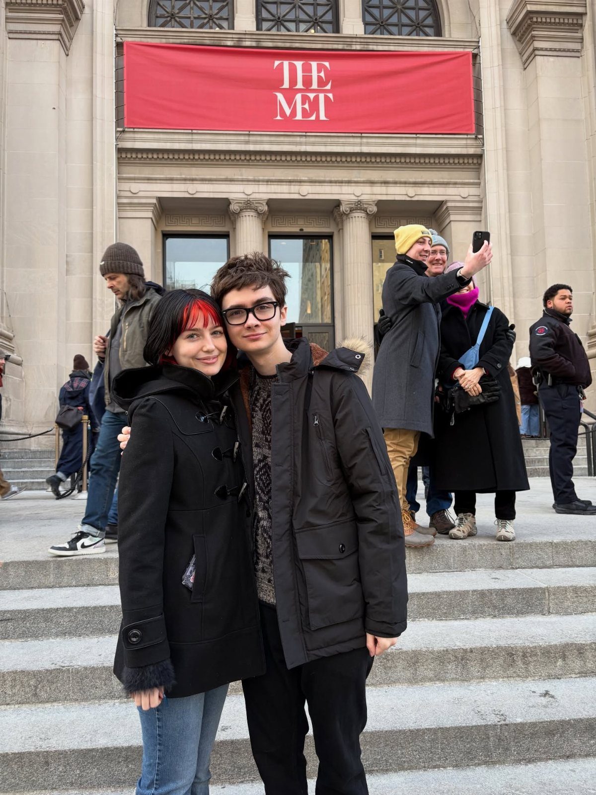 Young couple posing on the steps in front of The Met museum entrance.