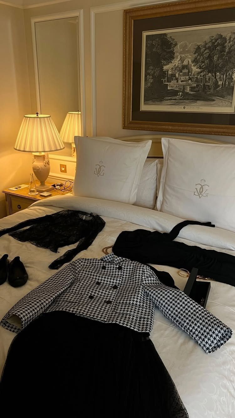 Houndstooth jacket and black skirt laid out on a white hotel bed.